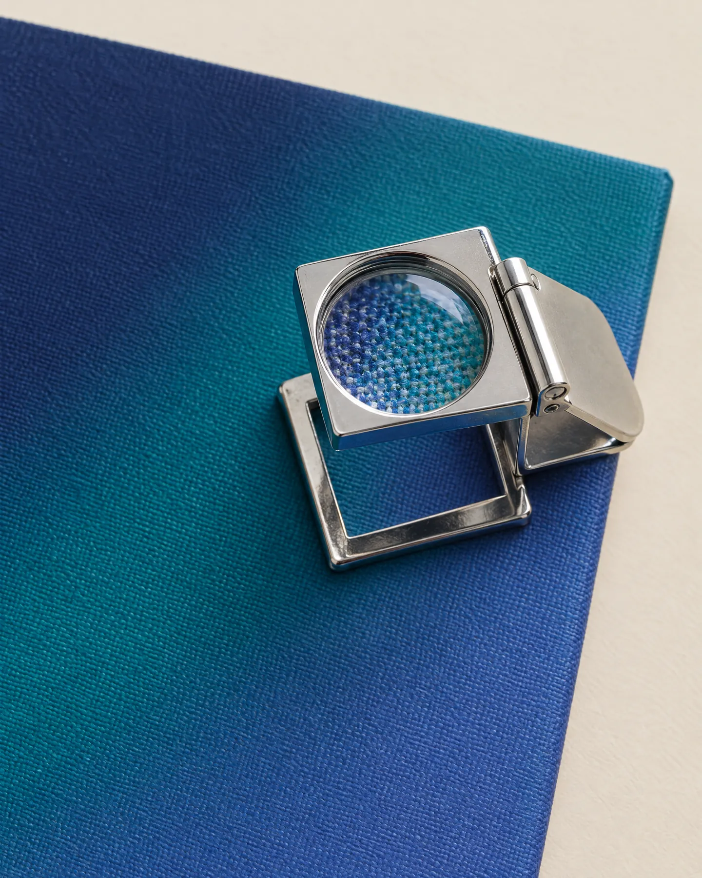 Printer’s loupe resting on a printed canvas, magnifying the threads and ink